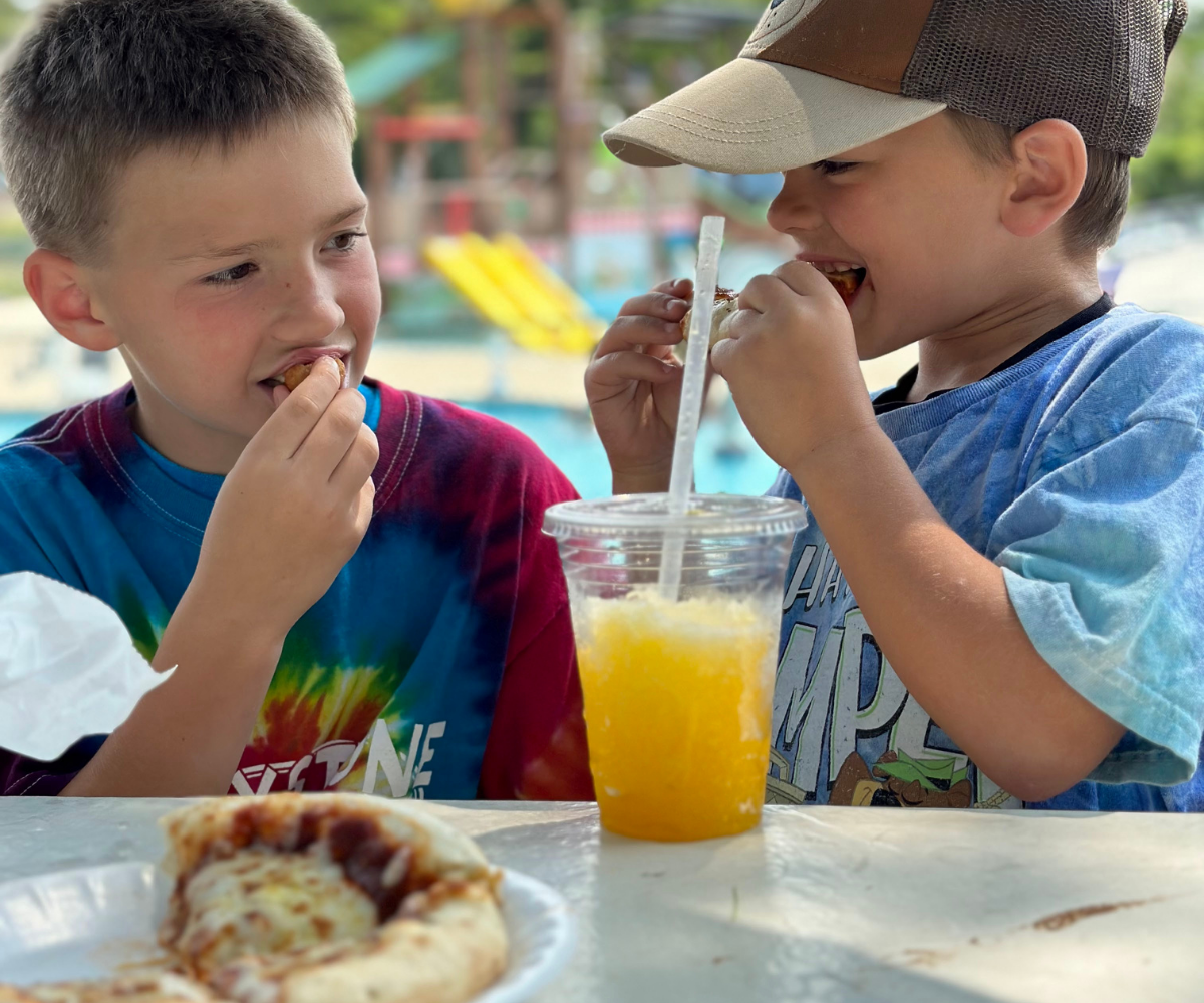 Two young campers enjoying pizza and slushies from the Pic-a-Nic Basket snack shop located at Jellystone Park™ Caledonia.