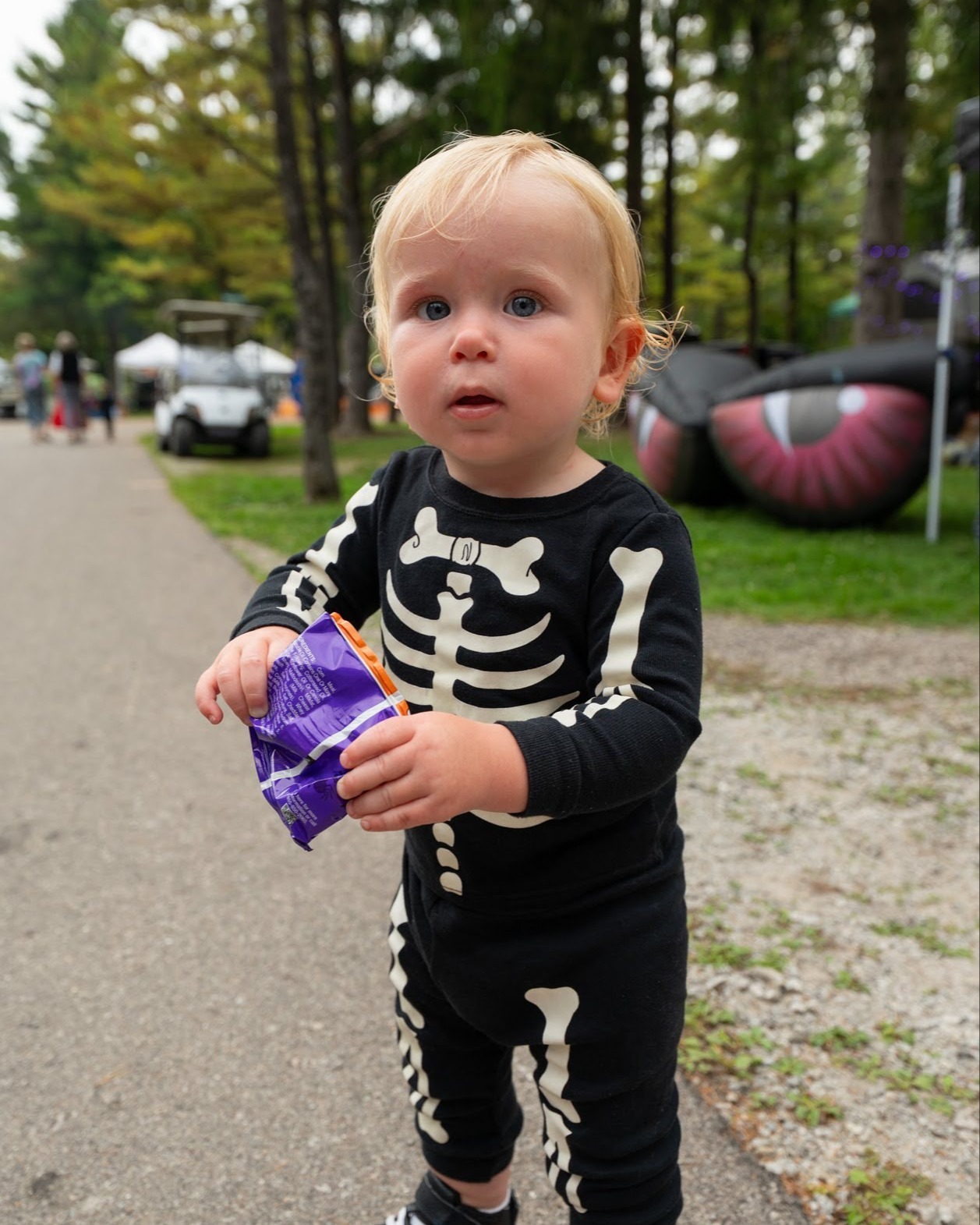 Toddler dressed as a skeleton poses for the camera during trick-or-treating at Jellystone Park™ Caledonia.