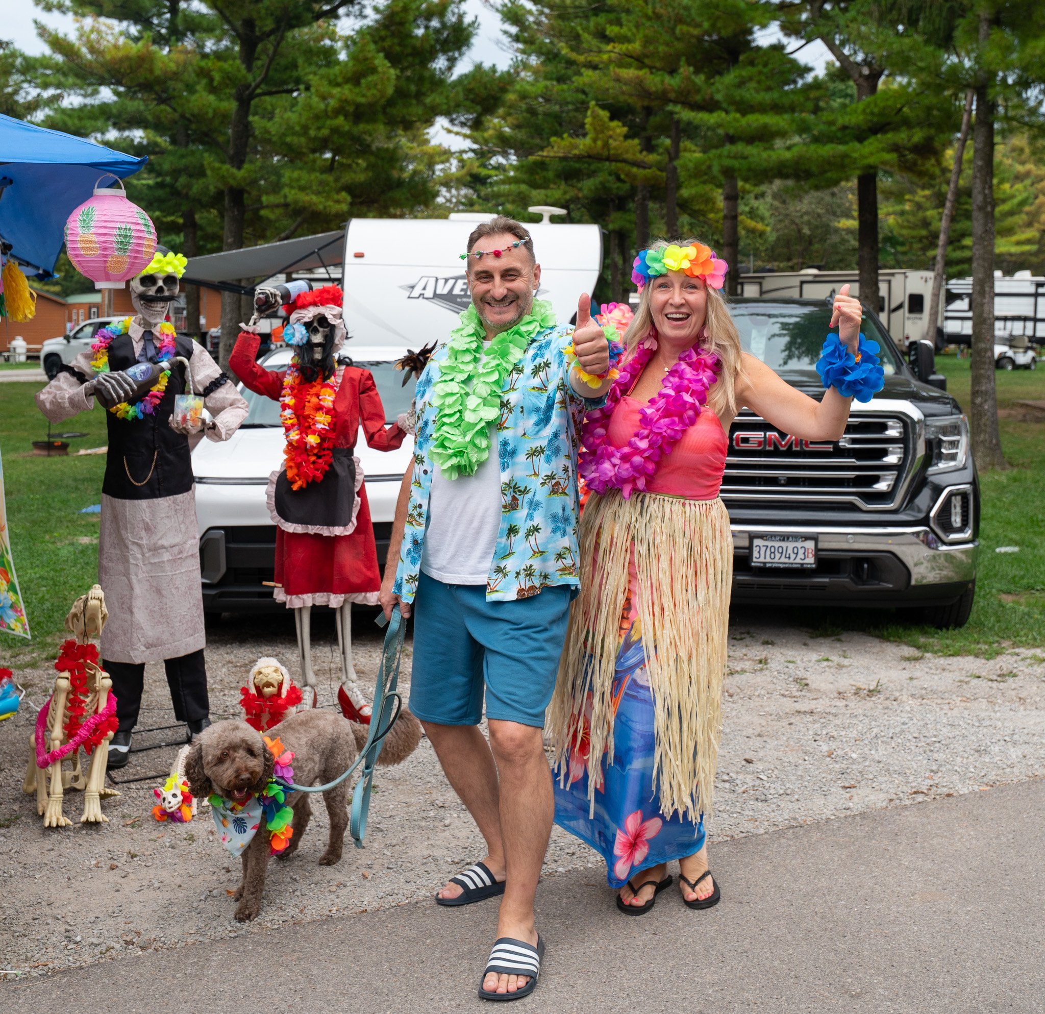 Smiling couple dressed as Hawaiian dancers enjoying trick-or-treating on a Halloween weekend at Jellystone Park™ Caledonia.