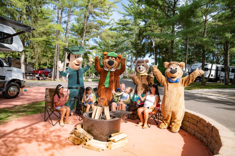 Family spending time around the campfire during their summer stay at Jellystone Park™ Caledonia.